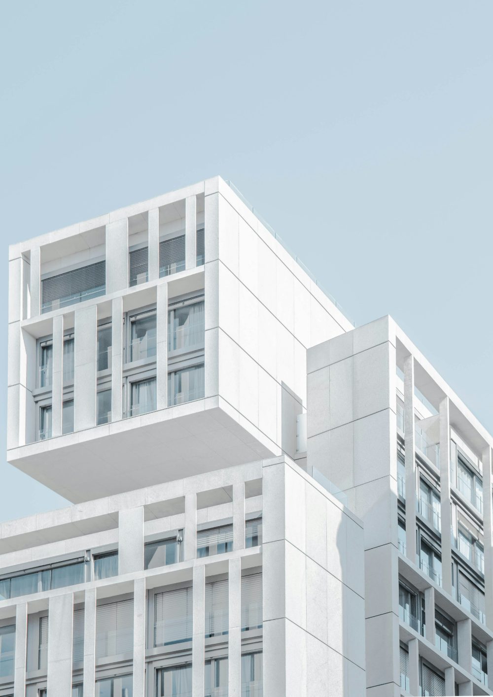 Weißes, minimalistisches Wohngebäude vor hellblauem Himmel